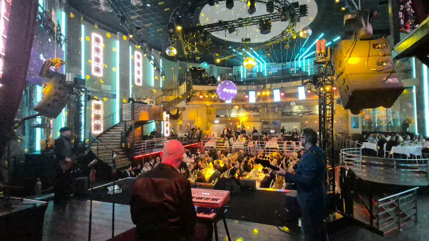Live-Band auf der Bühne vor festlich gedeckten Tischen in einer Club-Location