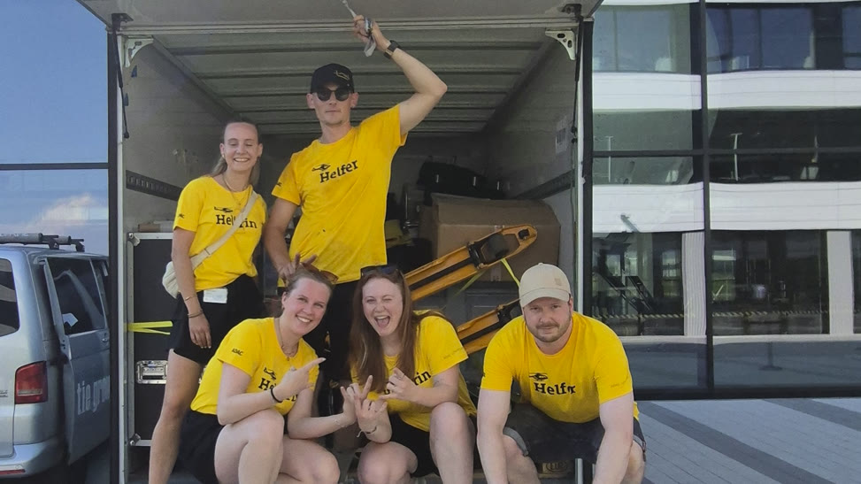Auf- und Abbauteam in gelben Helfer-Shirts auf der Ladefläche des Eventtrucks