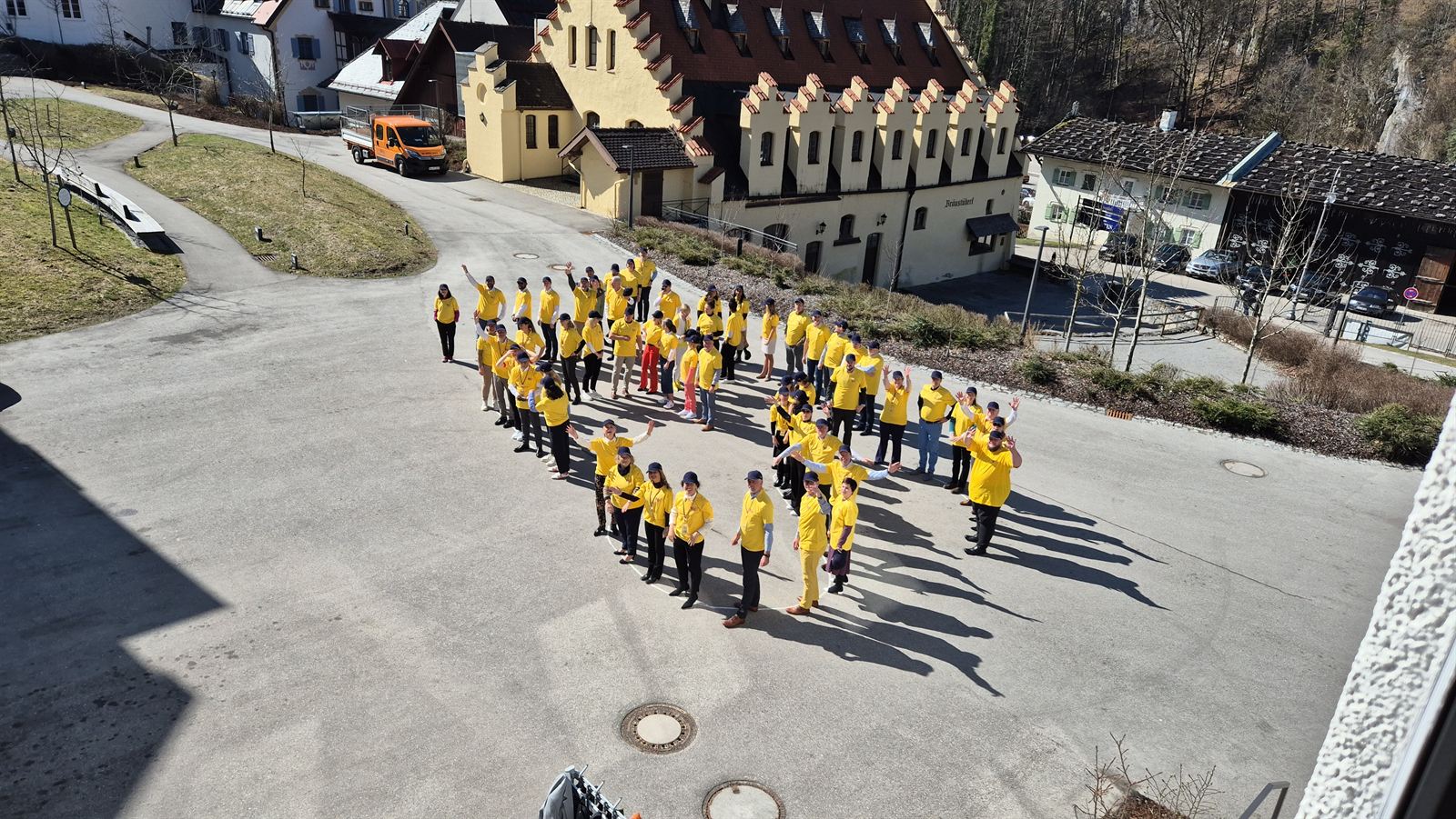 Team in gelben Shirts formiert einen Kreis vor Alpenkulisse